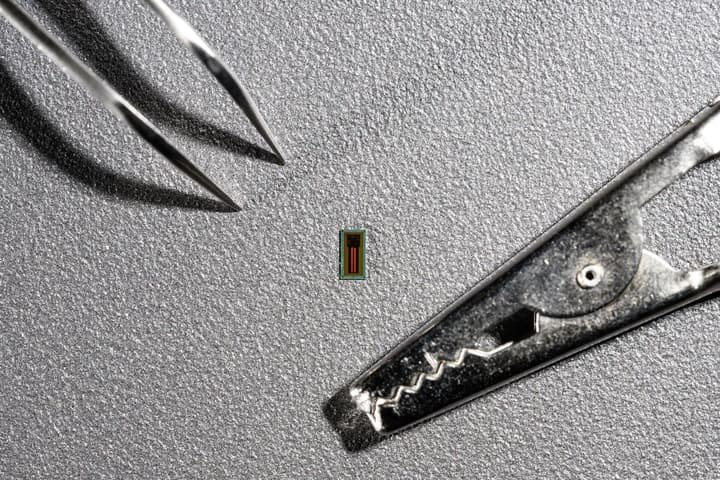 The new super-small MiBMI chip with a pair of tweezers and alligator clip for comparison