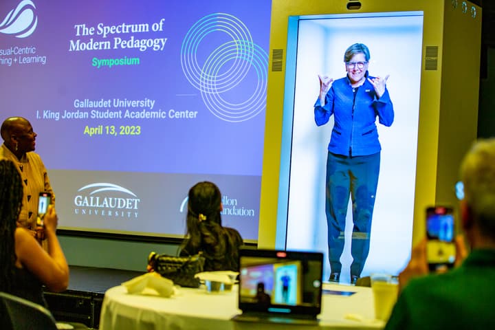 President of Gallaudet University Roberta J. Cordana engages with attendees at the Visual-Centric Teaching and Learning Symposium via a hologram projection machine developed by Proto Inc.